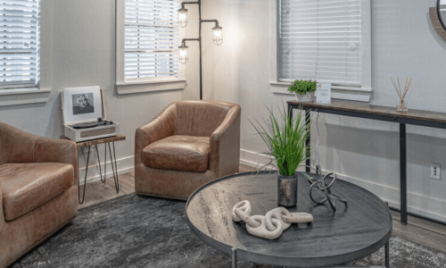 Modern apartment living area with two velvet armchairs, a round coffee table, and decorative elements, creating a cozy and stylish space.