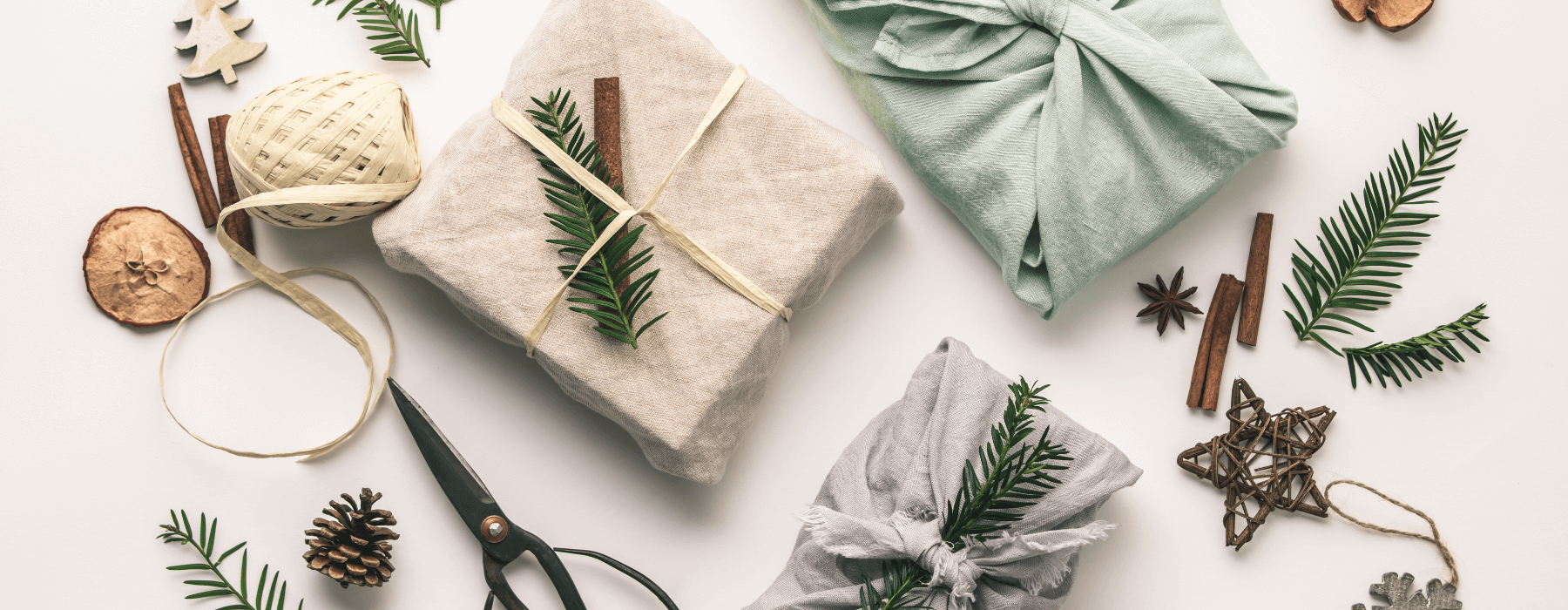 Sustainable holiday gifts wrapped in fabric with natural decorations like pine sprigs, cinnamon sticks, and twine, surrounded by eco-friendly wrapping materials.