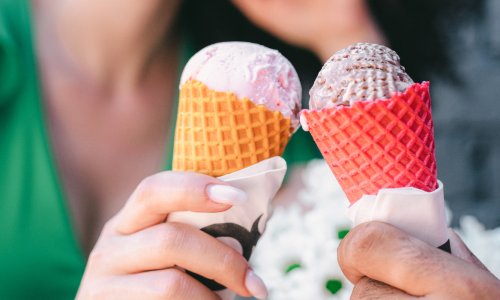 Two people holding colorful ice cream cones.