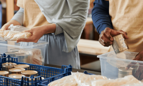 Volunteers packing canned food and bread into boxes, symbolizing community support and local aid efforts.